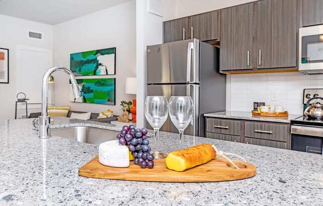 A kitchen with a granite countertop and a cheese and grapes platter.