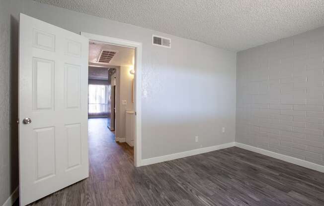 an empty living room with a white door and wood flooring