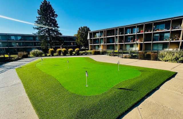 A small putting green in front of a building.