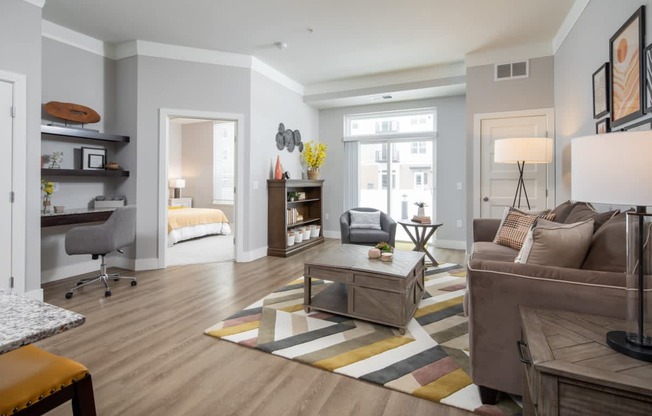 A modern living room with a grey couch, a coffee table, and a striped rug.