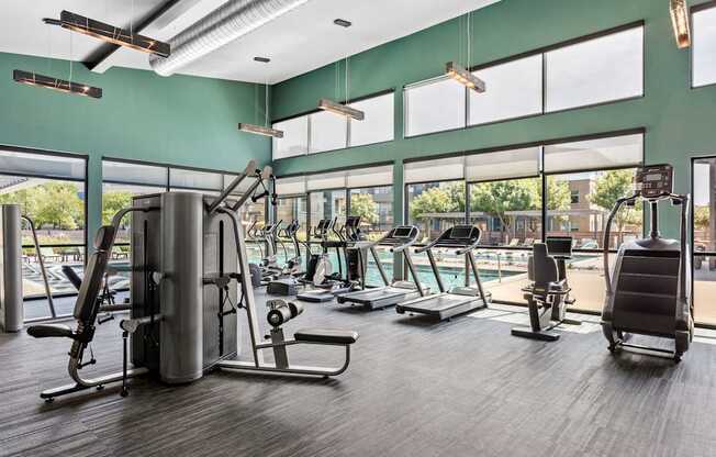 A gym with a variety of equipment including treadmills, weights, and a rowing machine.