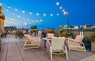 a roof top patio with chairs and tables and lights