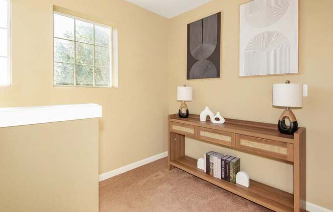 A landing with a tan wall and a wooden shelf with books and decorative items at The Landing Apartments and Townhomes, Oregon, 97045