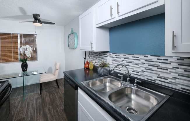 Fifteen 50 apartments kitchen in Las Vegas. White cabinets with modern silver pulls, dishwasher, and grey tone tile backsplash.