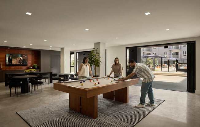 A man is playing pool in a room with a large window.