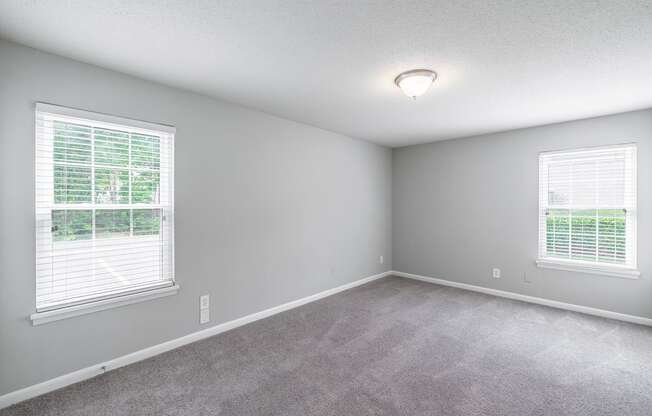 a bedroom with two windows and a carpeted floor