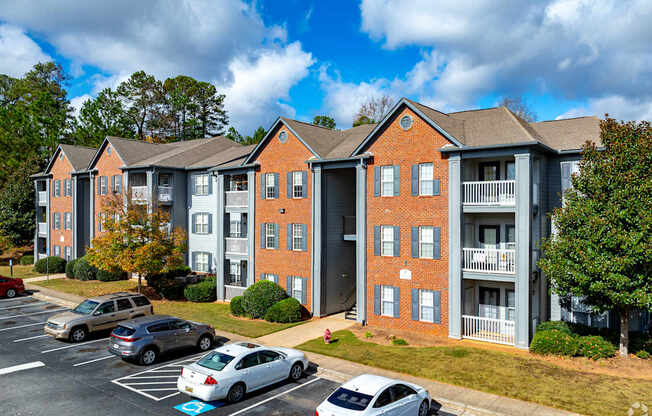 A parking lot in front of a brick apartment building.