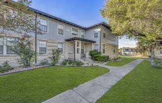 a sidewalk in front of a building with grass and trees  at Sunset Ridge, San Antonio, 78209