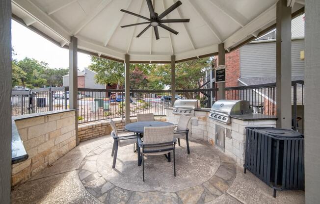 a covered patio with a table and chairs and a grill