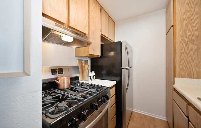 a kitchen with a stove and refrigerator and wooden cabinets