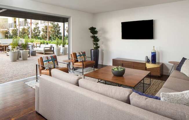 A living room with a grey couch, a wooden coffee table, and a flat screen TV mounted on the wall.