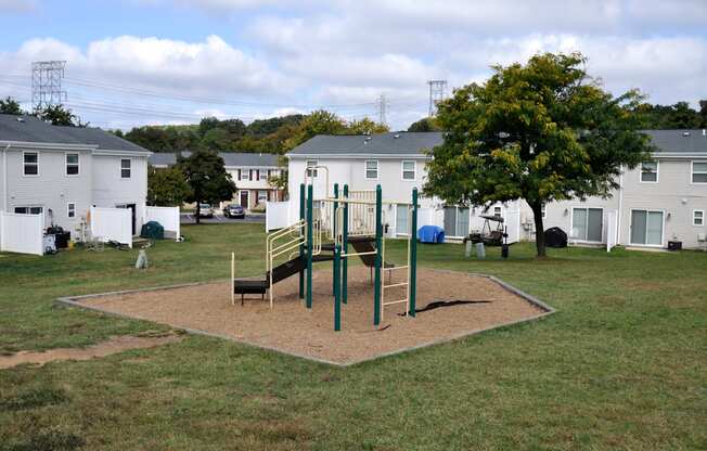 A playground with a swing set and a slide in the middle of a grassy area.
