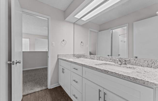 A bathroom with a marble countertop and white cabinets.
