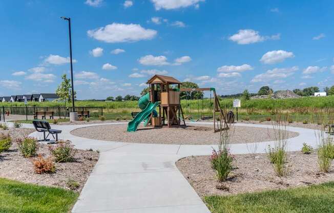 A playground with a green slide and a wooden structure.