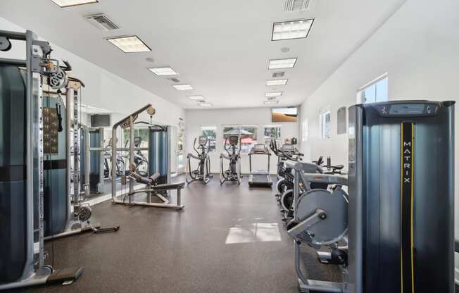 a gym with cardio equipment and weights on the floor