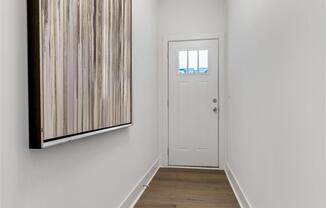 a hallway with a white door and a painting on the wall