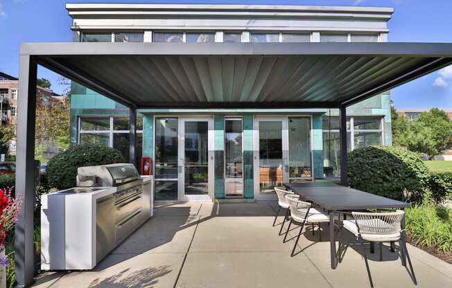 a patio with a barbecue grill and a table and chairs