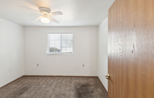 an empty bedroom with a closet and a ceiling fan