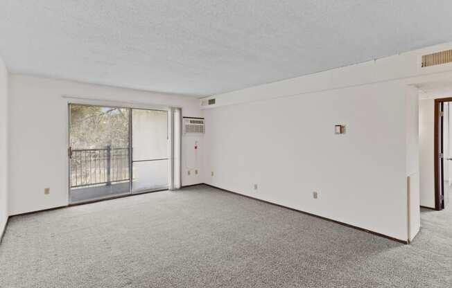 an empty living room with a sliding glass door and a balcony