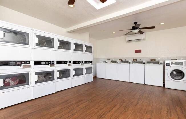 A laundry room with a row of washers and dryers.