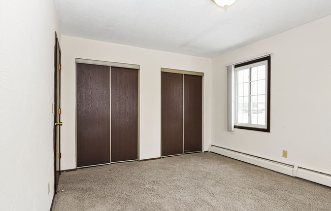 an empty room with a window and two closet doors. Fridley, MN Georgetown on the River Apartments