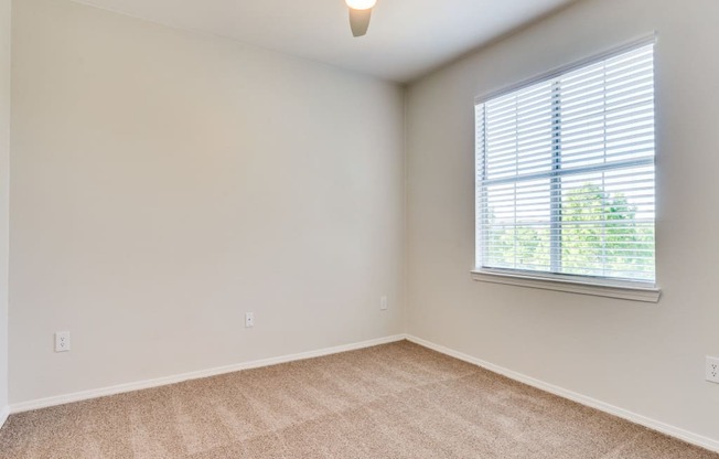 a bedroom with a ceiling fan and a window at Arioso apartments located at 3030 Claremont Dr in Grand Prairie, TX