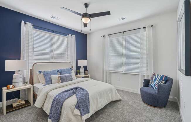 A bedroom with a bed, chair, and ceiling fan.