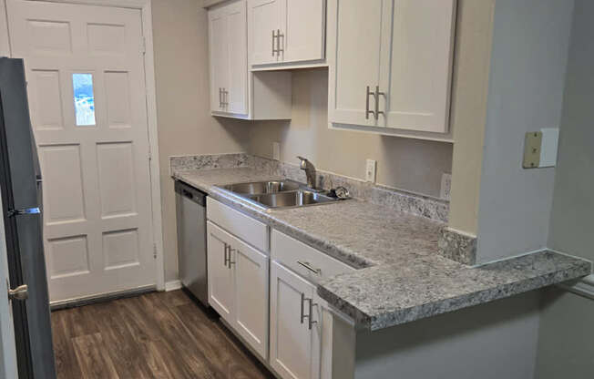 A kitchen with a granite countertop and white cabinets.