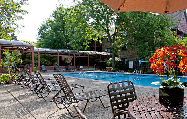 Outdoor pool with lounge chairs, umbrella tables, and shaded areas