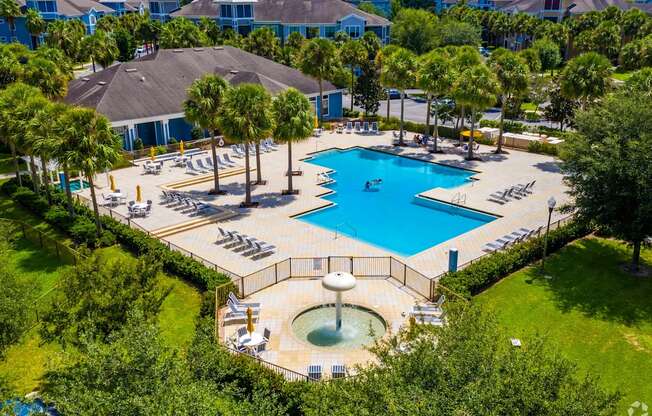 A large swimming pool surrounded by trees and a hot tub.