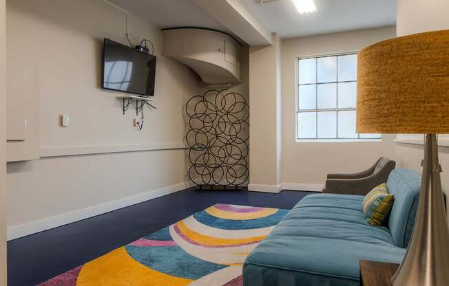 A bedroom with a blue bed and a television on the wall.