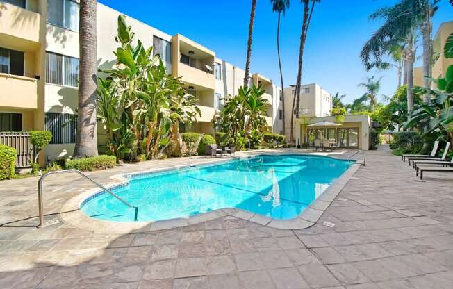 a large swimming pool in front of a hotel with palm trees