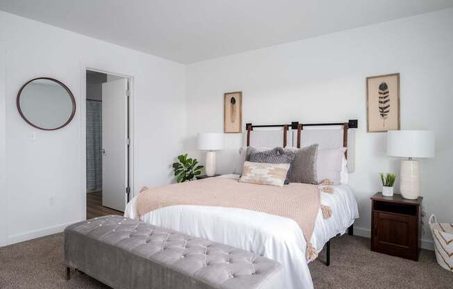 A bedroom with a large bed and a grey ottoman.