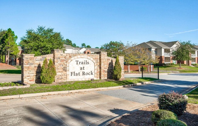 A sign that says Trails at Flat Rock stands in front of a gated entrance.
