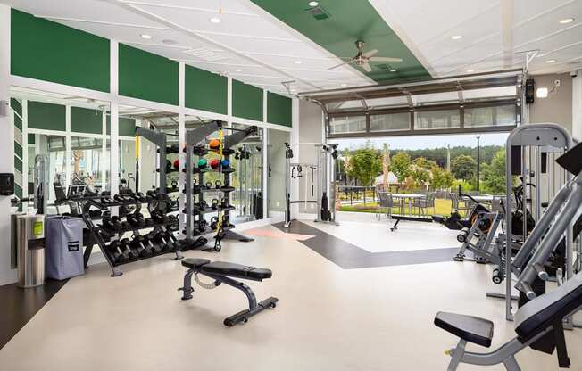 Fitness Center with the garage door open leading to patio seating outside at Carmel Vista, McDonough, GA