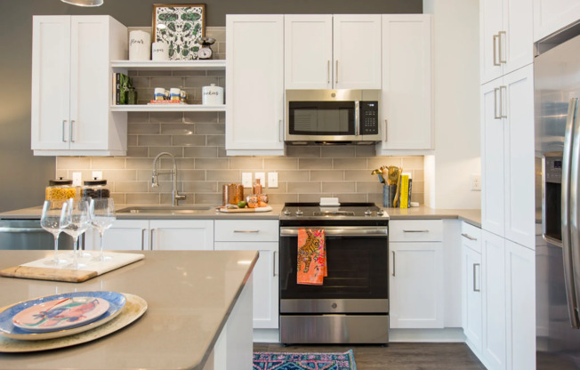 A kitchen with white cabinets, under-cabinet task lighting. and stainless steel appliances.