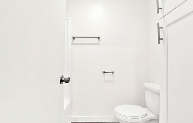 A white toilet sits in a bathroom next to a towel bar.