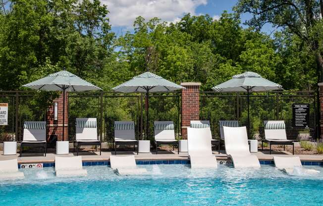 a swimming pool with chairs and umbrellas next to it