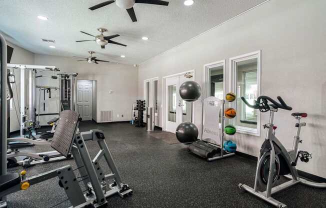 a home gym with weights and cardio machines and a ceiling fan