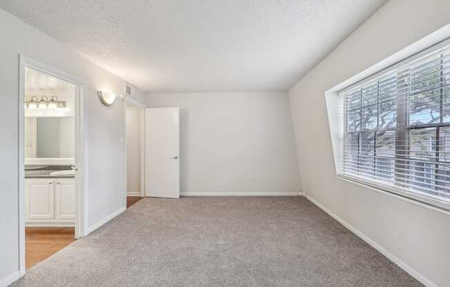 A room with a carpeted floor and a window with blinds.