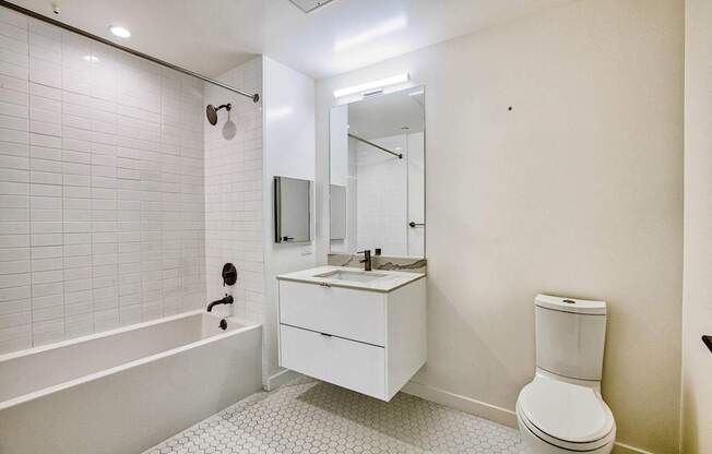A white bathroom with a toilet, sink, and bathtub.at The Dillon, Los Angeles, 90026