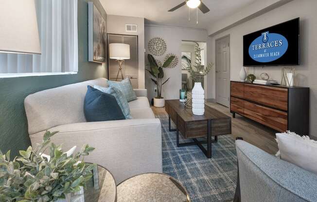 Living room with fan, large windows, model décor, and wood-style floors at Terraces at Clearwater Beach, Florida, 33756