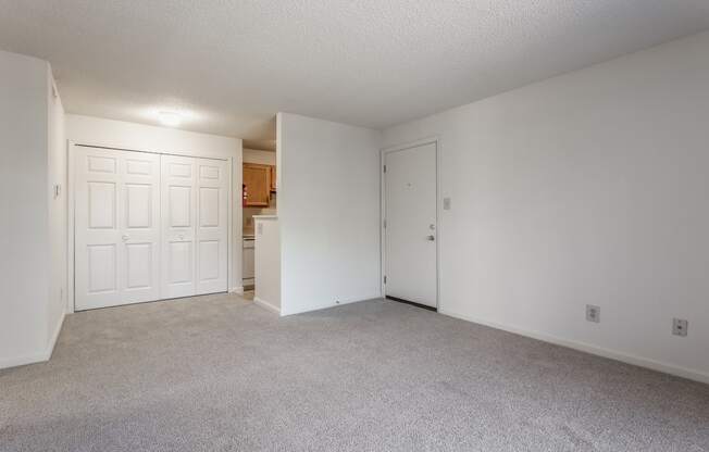 an empty bedroom with a kitchen in the background