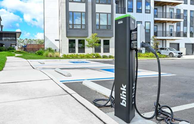 a hybrid electric vehicle plugged into a charging station in front of an apartment building