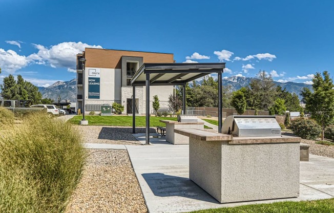 a picnic area with a grill and a building with mountains in the background
