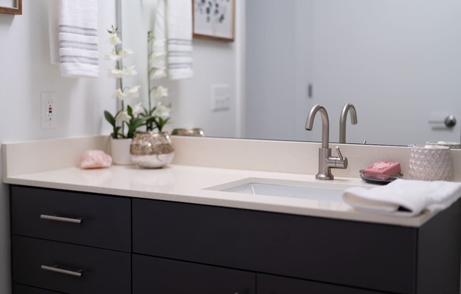 A bathroom sink with a white counter top and a silver faucet.