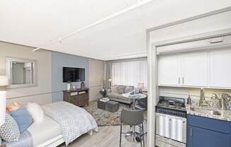 kitchen with stainless steel appliances, white and navy cabinets, and living space