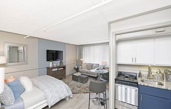 kitchen with stainless steel appliances, white and navy cabinets, and living space