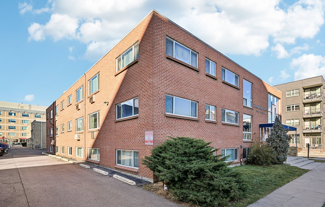 Charming brick apartment building with ample natural light and lush landscaping, perfect for modern urban living.