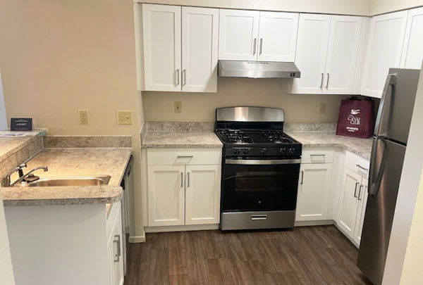 a renovated two bedroom two bath kitchen with white cabinets at Canal Club Apartments, Lansing, MI